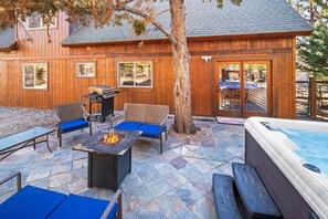 An outdoor patio with a hot tub, fire pit, and seating area.