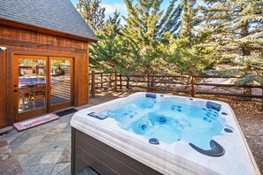 Una cabaña de madera con jacuzzi en un entorno natural.