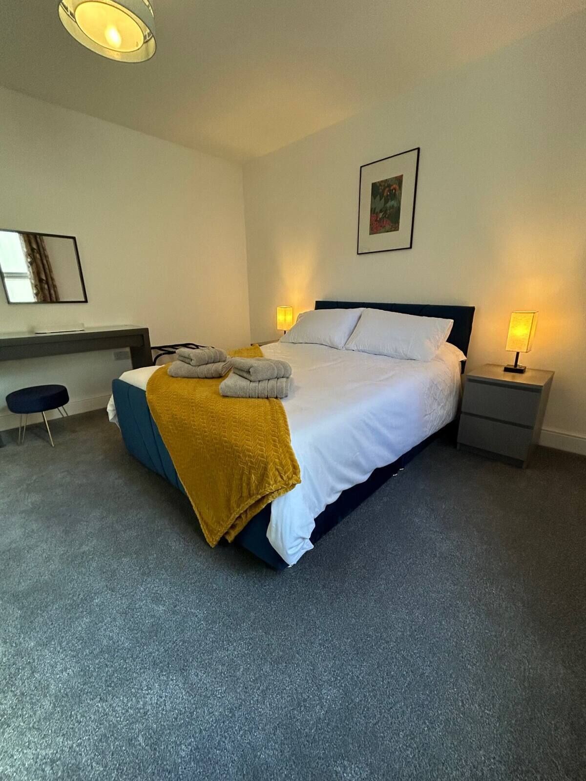 Ein modernes Hotelzimmer mit einem großen Bett, Nachttischlampen, einem Schreibtisch und einem Stuhl.