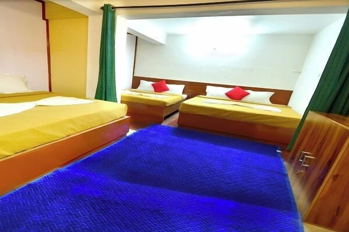 A hotel room with two beds, a blue carpet, and wooden furniture.