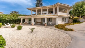 A two-story house with a covered patio, outdoor seating, and a gravel driveway. - Villa Plemmiria by the Sea by Wonderful Italy (Syracuse)