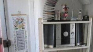 Una habitació amb una porta blanca, una estanteria amb llibres i un ventilador, i un cartell a la paret.