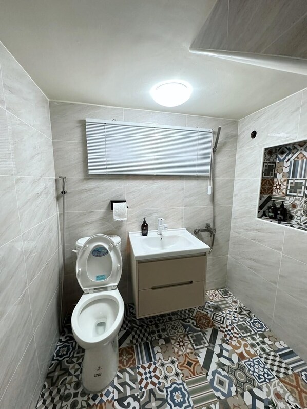 A small bathroom with a toilet, sink, and shower. - Here after us (Dahu)