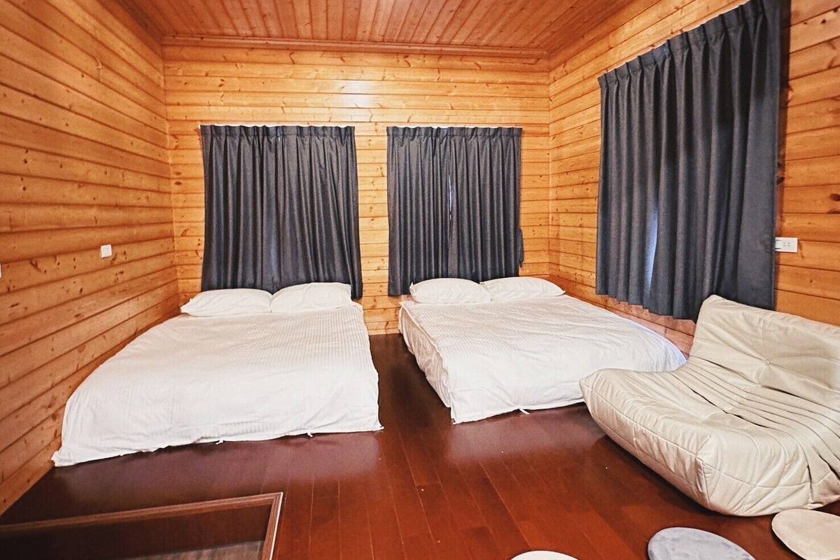 A cabin-style room with two single beds, a sofa, and a small table.