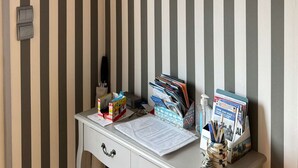 A room with striped wallpaper, a desk with various items, a small arched window, and a door. - Le Rivage, House with garden near the sea (Saint-Aubin-sur-Mer)