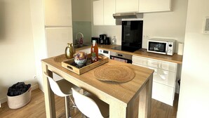 A compact kitchen with white cabinets, a microwave, a coffee maker, and a small refrigerator. - Apartment "Le Clémenceau", downtown, fully equipped (Saint-Brieuc)