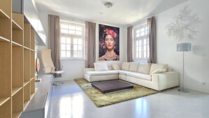 A modern living room with a sectional sofa, a coffee table, a floor lamp, and a large window with curtains. - Apartment in villa, sky view, elevator, luxury floor (Bad Hall)