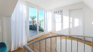 A bright room with a large sliding glass door, a white door, and a ceiling light fixture.