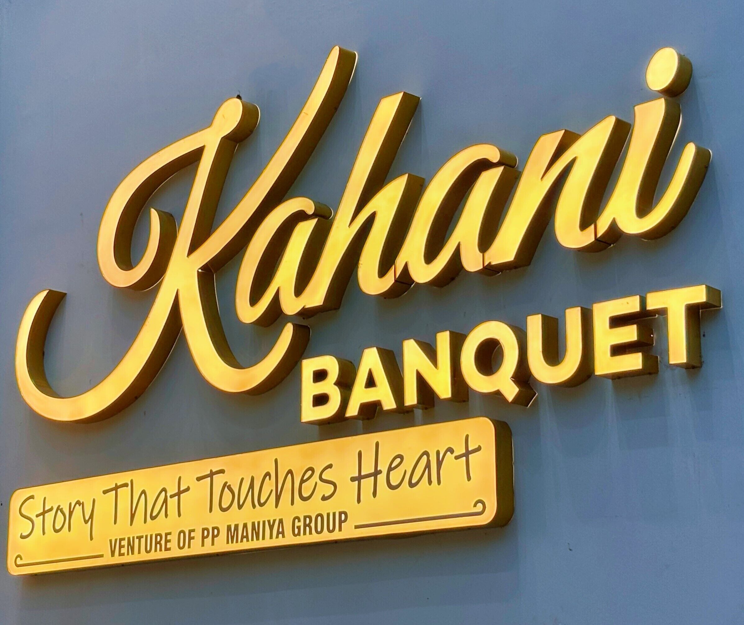 A sign for 'Kahani Banquet' with a slogan 'Story That Touches Heart' and mentions 'Venture of PP Maniya Group'.