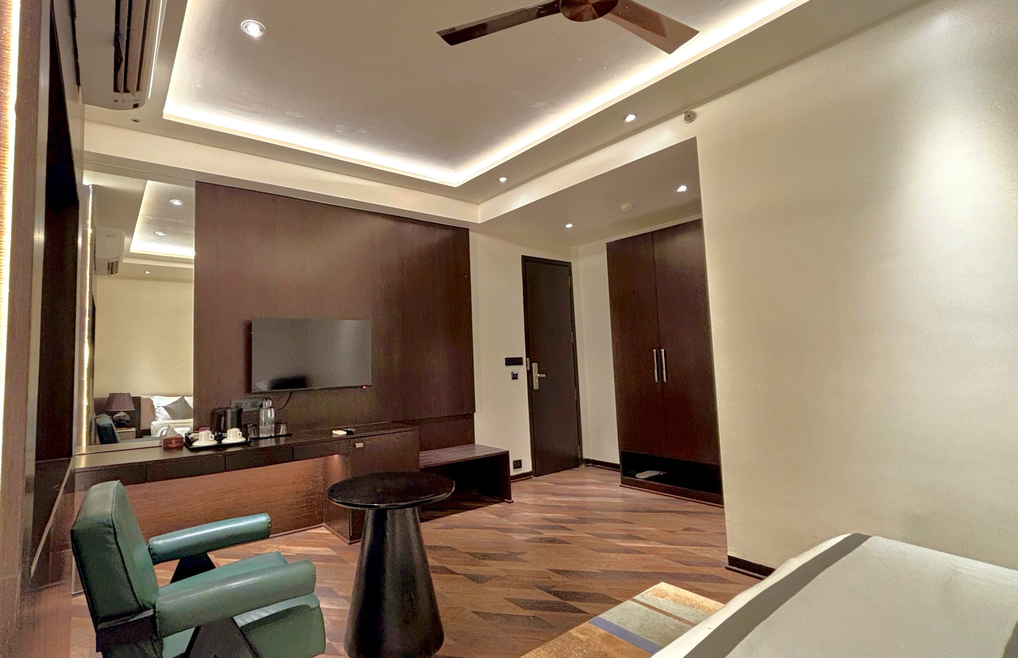 Ein modernes Hotelzimmer mit Flachbildfernseher, einer Couch, einem Couchtisch und einem Deckenventilator.