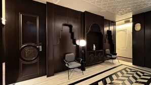 Un corridoio con rivestimenti in legno scuro, due poltrone, un elemento decorativo a parete e un pavimento a motivi.