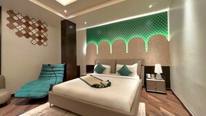 Una camera da letto moderna con un ampio letto, una chaise longue, un comodino e un elemento decorativo a parete.