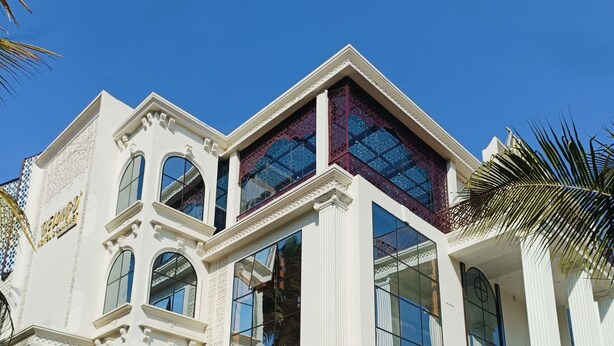 Un grande edificio bianco con numerose finestre e un cartello con la scritta "The Long's Hotel & Banquet".