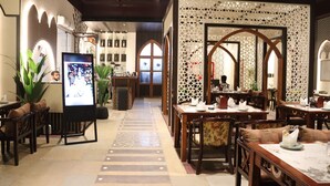 Un ristorante con una disposizione lunga e stretta, caratterizzato da tavoli e sedie in legno, pavimento piastrellato e pannelli decorativi a parete.