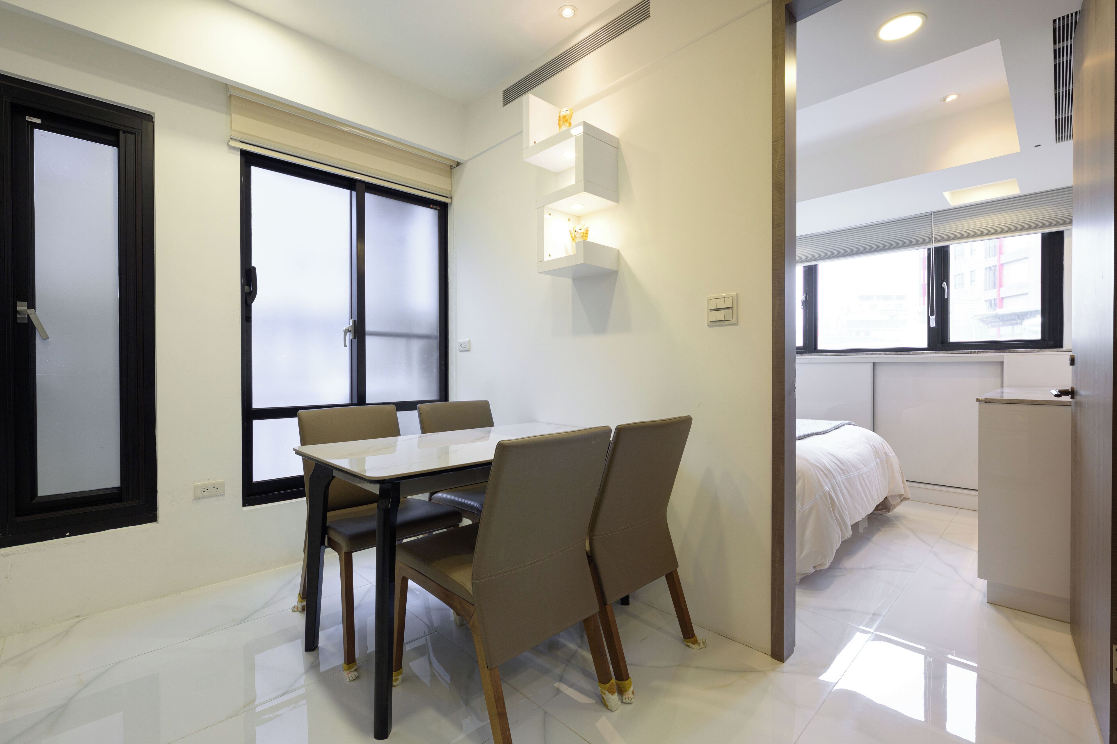 A modern hotel room with a dining area, a bed, and a small kitchenette.