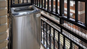 Ein Zimmer mit großem Fenster, Metallgeländer und einer Waschmaschine.