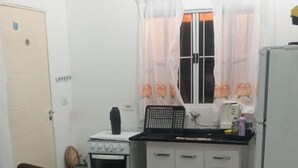 A compact living space with a kitchenette, a sofa, and a patterned rug. - Life Ibiuna space with swimming pool, barbecue and peace (Ibiúna)
