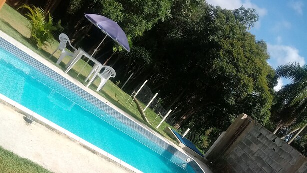 A swimming pool with a slide, surrounded by grass and trees. - Life Ibiuna space with swimming pool, barbecue and peace (Ibiúna)