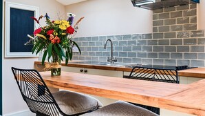 Een moderne keuken met een houten aanrechtblad, een inbouwgootsteen en een backsplash van baksteen.
