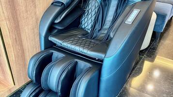 A massage chair with a control panel and footrest.