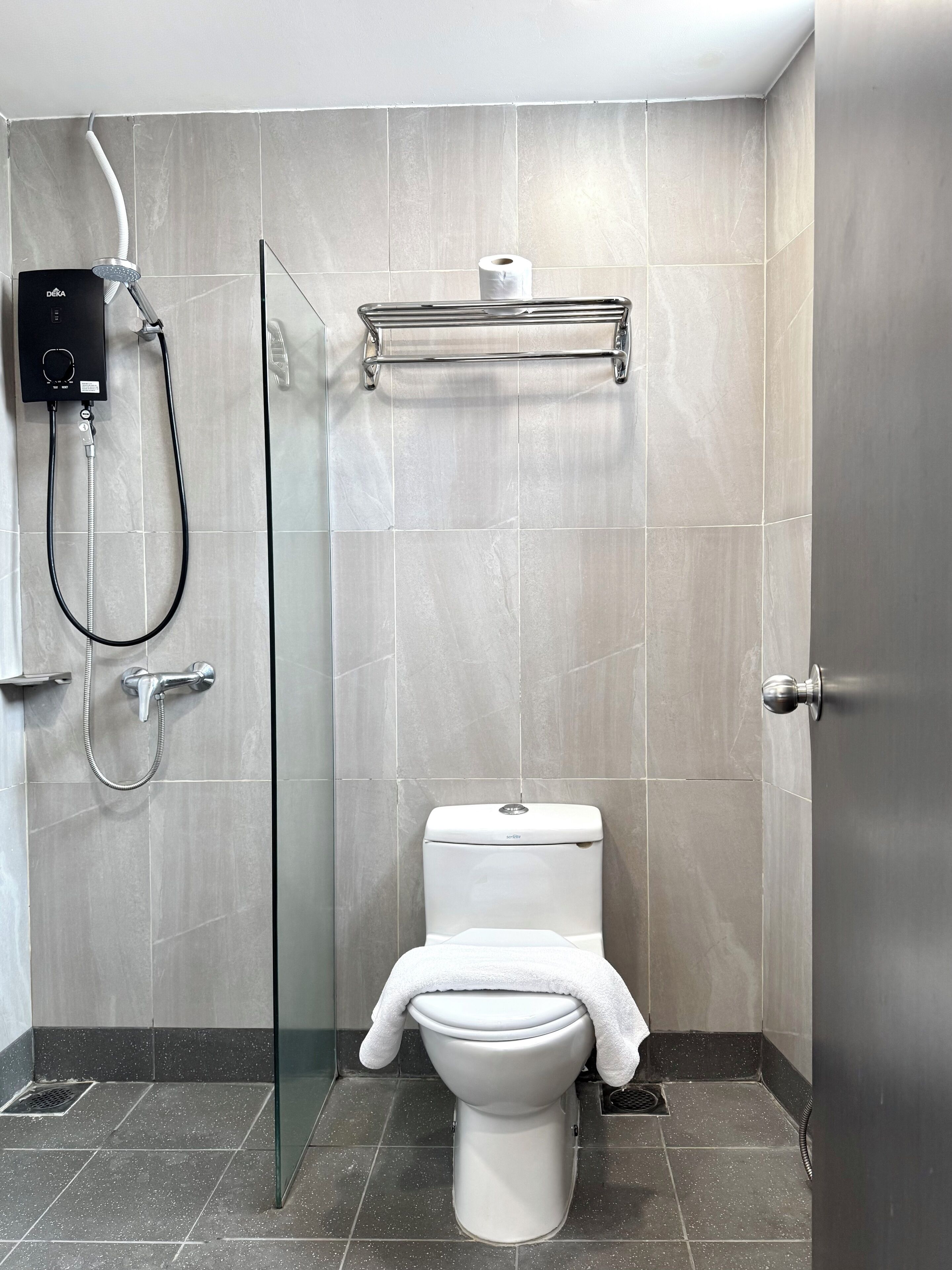 A modern bathroom with a glass shower enclosure, a toilet, and a towel rack.