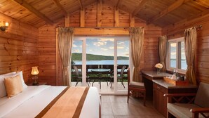 Una habitación de cabaña de madera con una cama, un escritorio y vista a un lago.