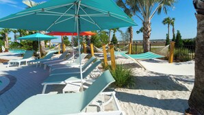 A beachside area with lounge chairs and umbrellas, palm trees, and a pool in the background. - Windsor Island 5BR Waterpark free (Davenport)