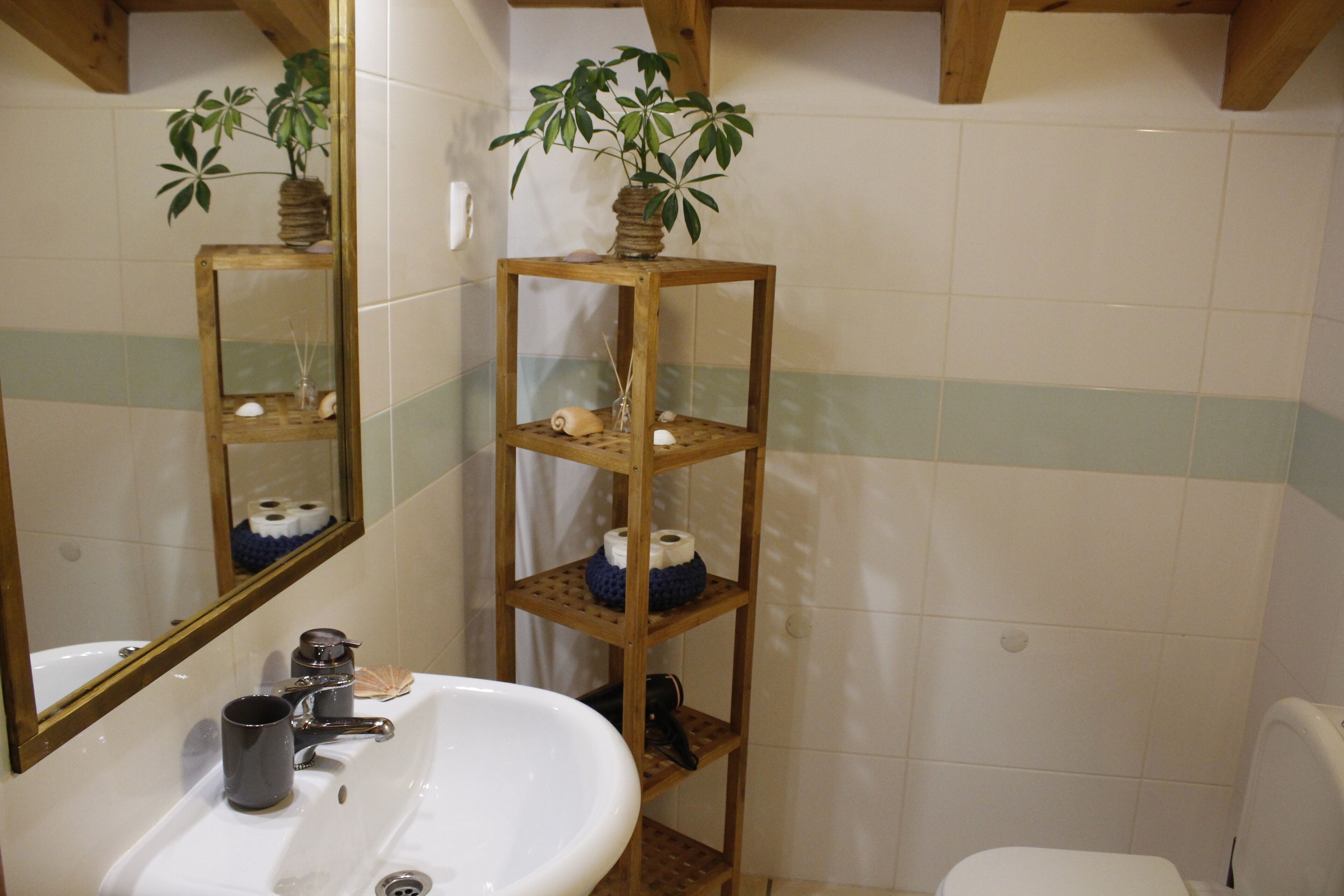 Een badkamer met een houten plank met toiletartikelen, een wastafel met spiegel en een toilet.