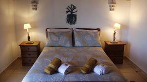 A bedroom with a bed, two nightstands, a wall-mounted tree decoration, and two wall-mounted lamps. - Casa Delbon (Aljezur)
