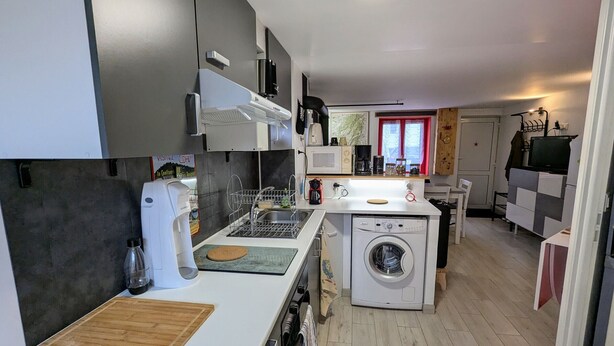 A compact kitchen with a microwave, coffee maker, and washing machine.