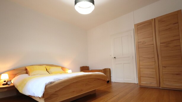 Une chambre à coucher avec un lit en bois, une table de chevet avec une lampe et une armoire.