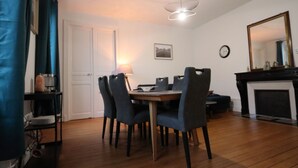 Un coin repas comprenant une table en bois, quatre chaises, une lampe, une horloge et une cheminée.