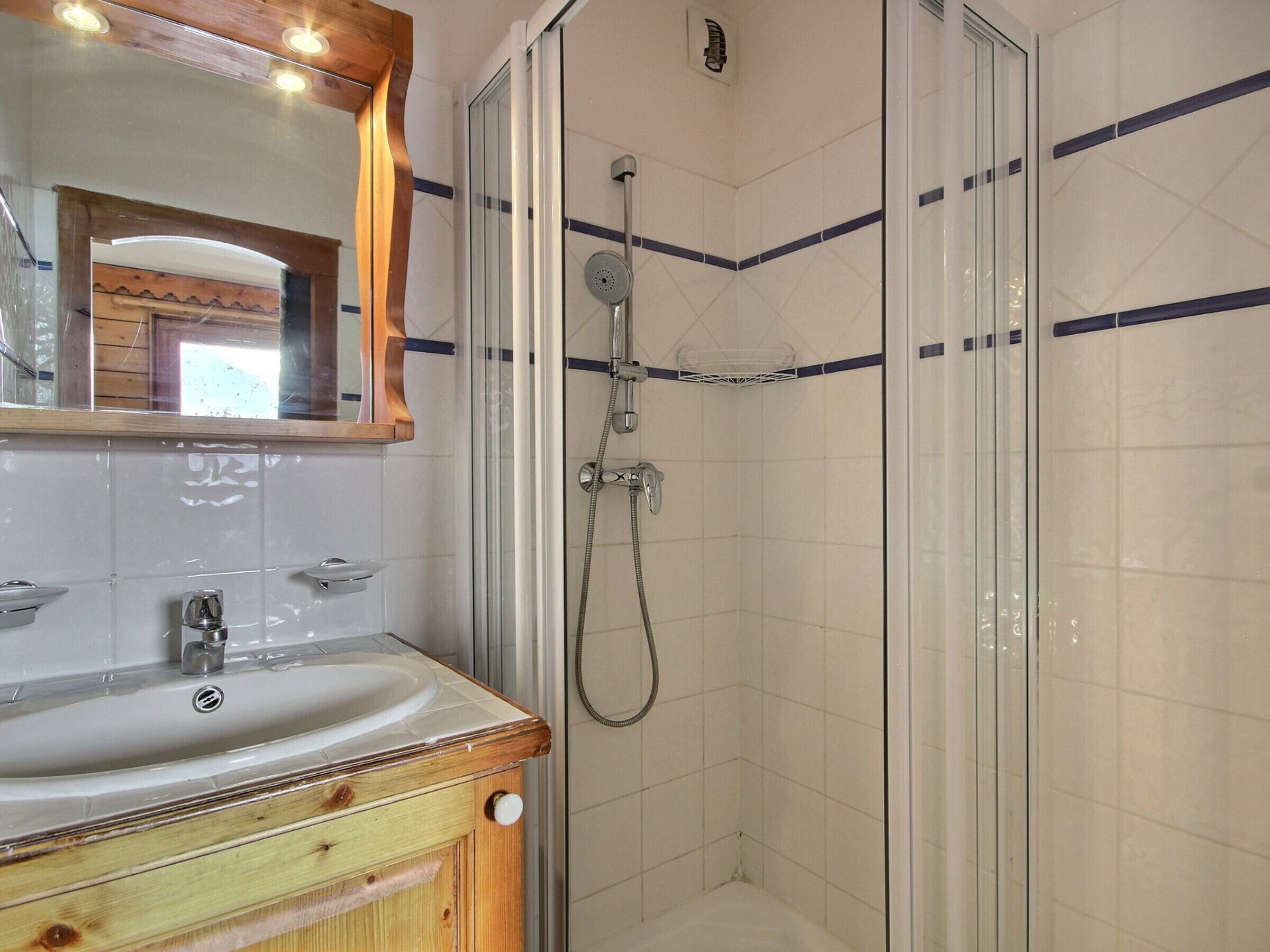 A bathroom with a wooden vanity, a sink, and a glass-enclosed shower area.