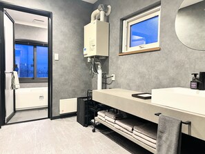 Bathroom features a large window, heater, and towel rack with neatly folded towels.