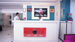 Una recepción de hotel con un reloj digital que muestra la hora 1:08:16, un logotipo con una corona y el texto "Hotel Stay Inn".