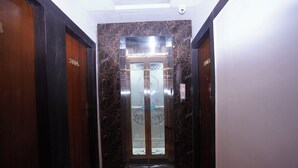 Un pasillo con un ascensor de mármol y puertas de madera.