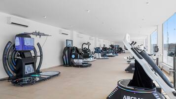 Et fitnesscenter med forskellige træningsmaskiner, herunder løbebånd og motionscykler, i en rummelig indretning.