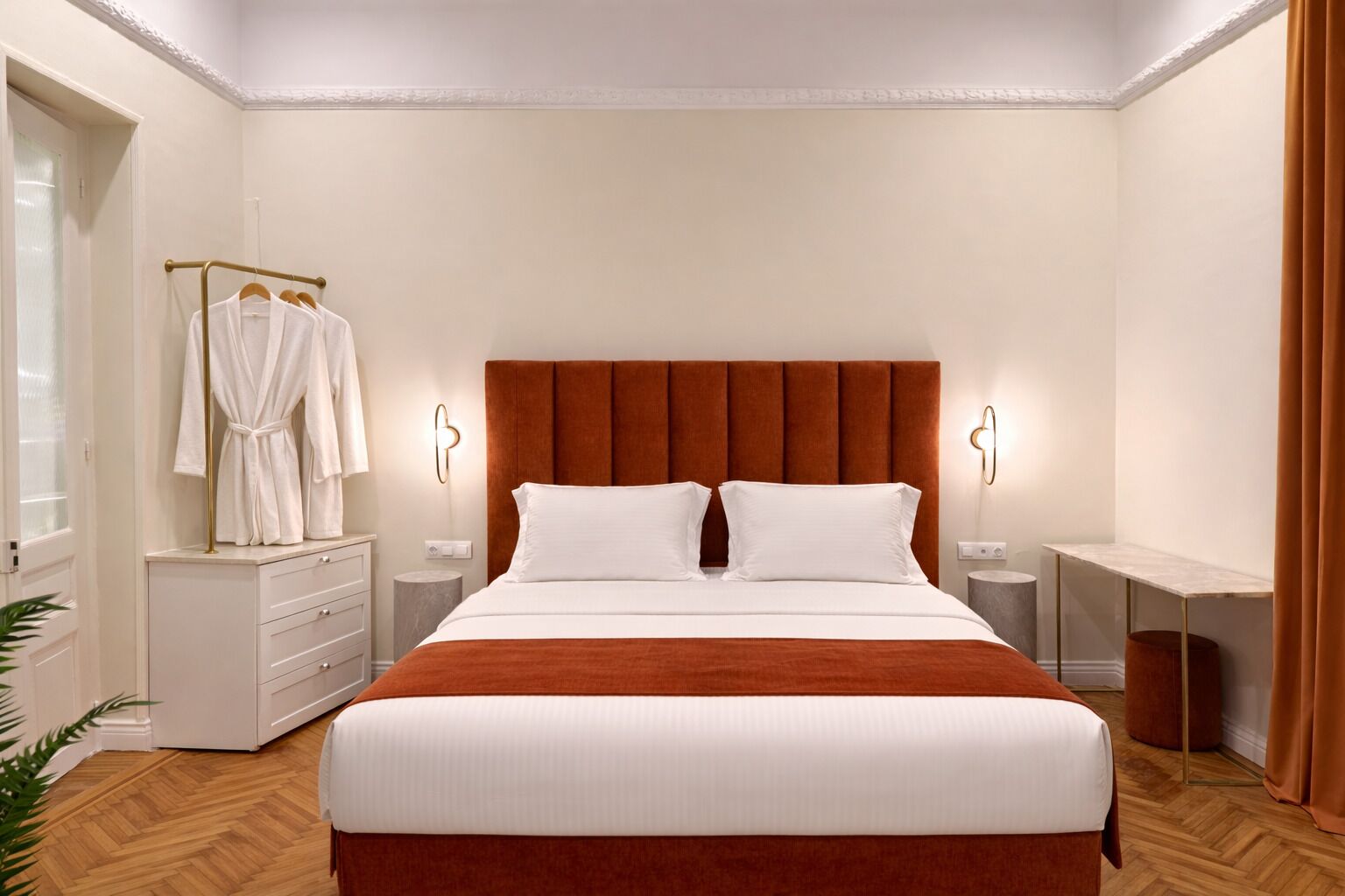 Une chambre d’hôtel avec un lit, des tables de chevet, un porte-peignoir et une plante.