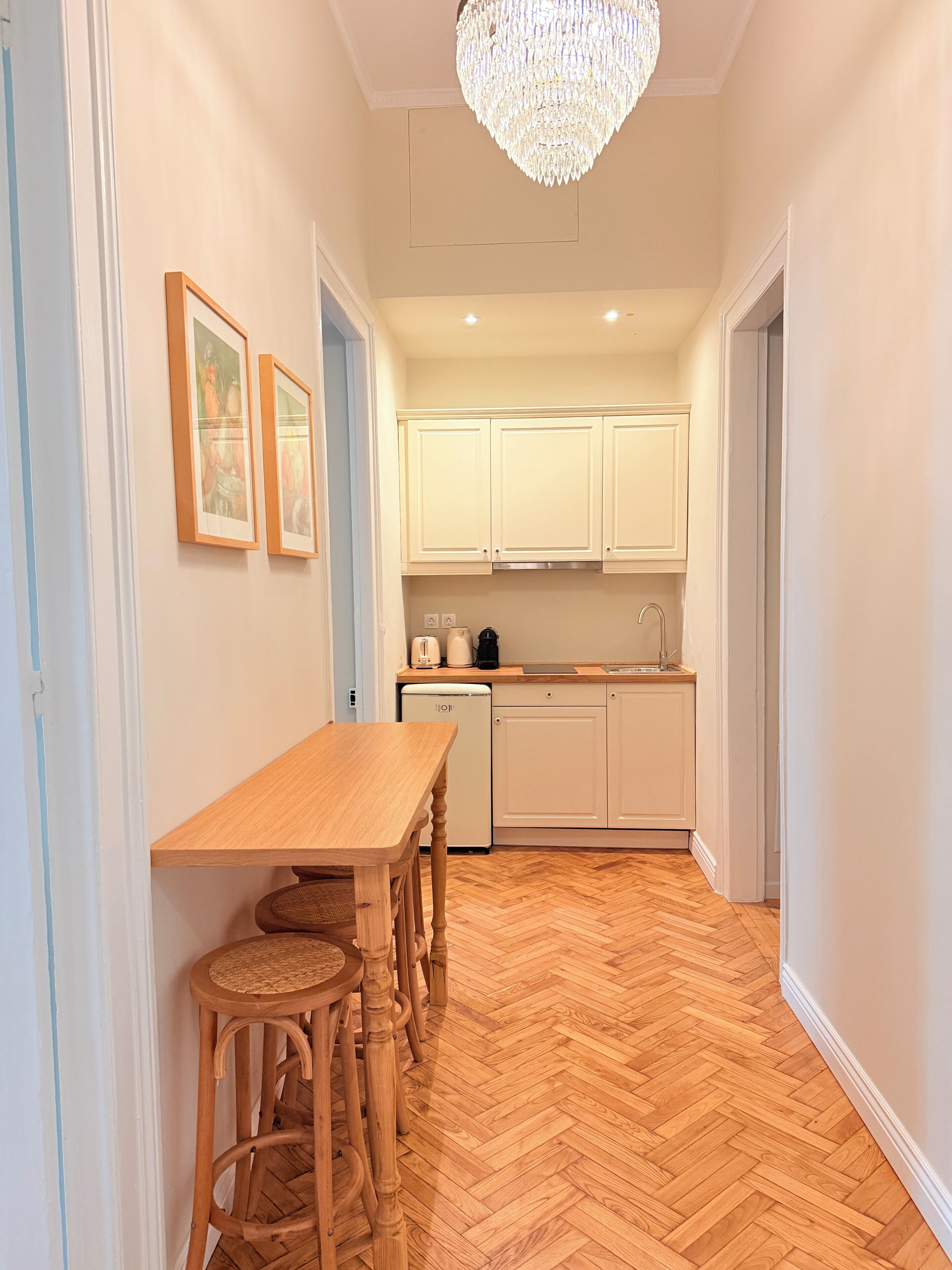 A kitchen with white cabinets, a wooden dining table, and a herringbone floor.