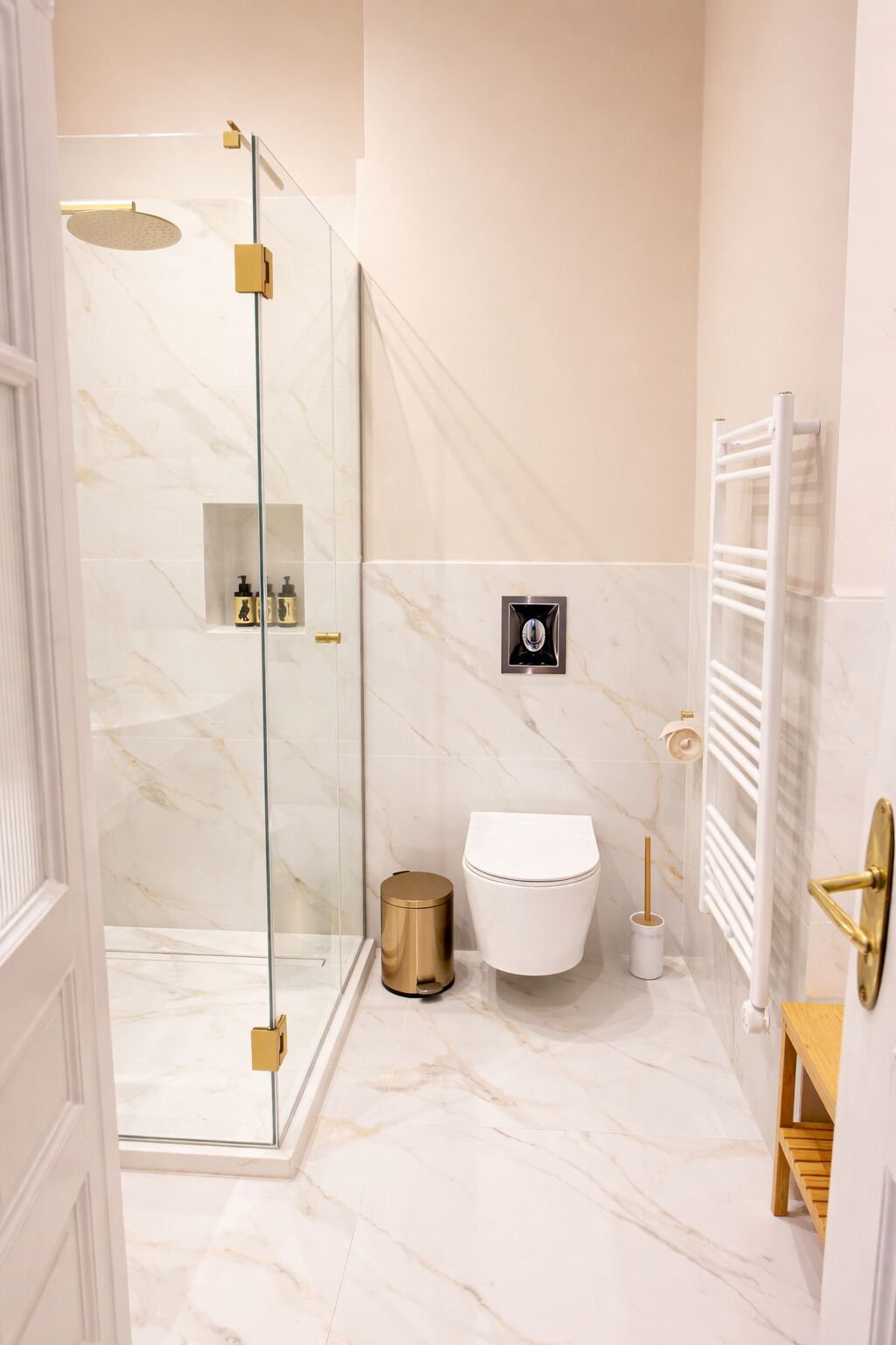 Un baño con cabina de ducha de vidrio, inodoro, toallero y un pequeño estante con artículos de aseo.