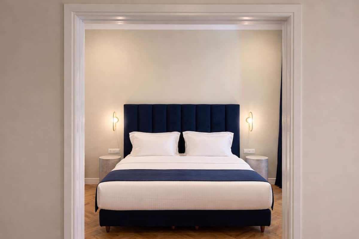 A bedroom with a large bed, two bedside tables, and wall-mounted lights.