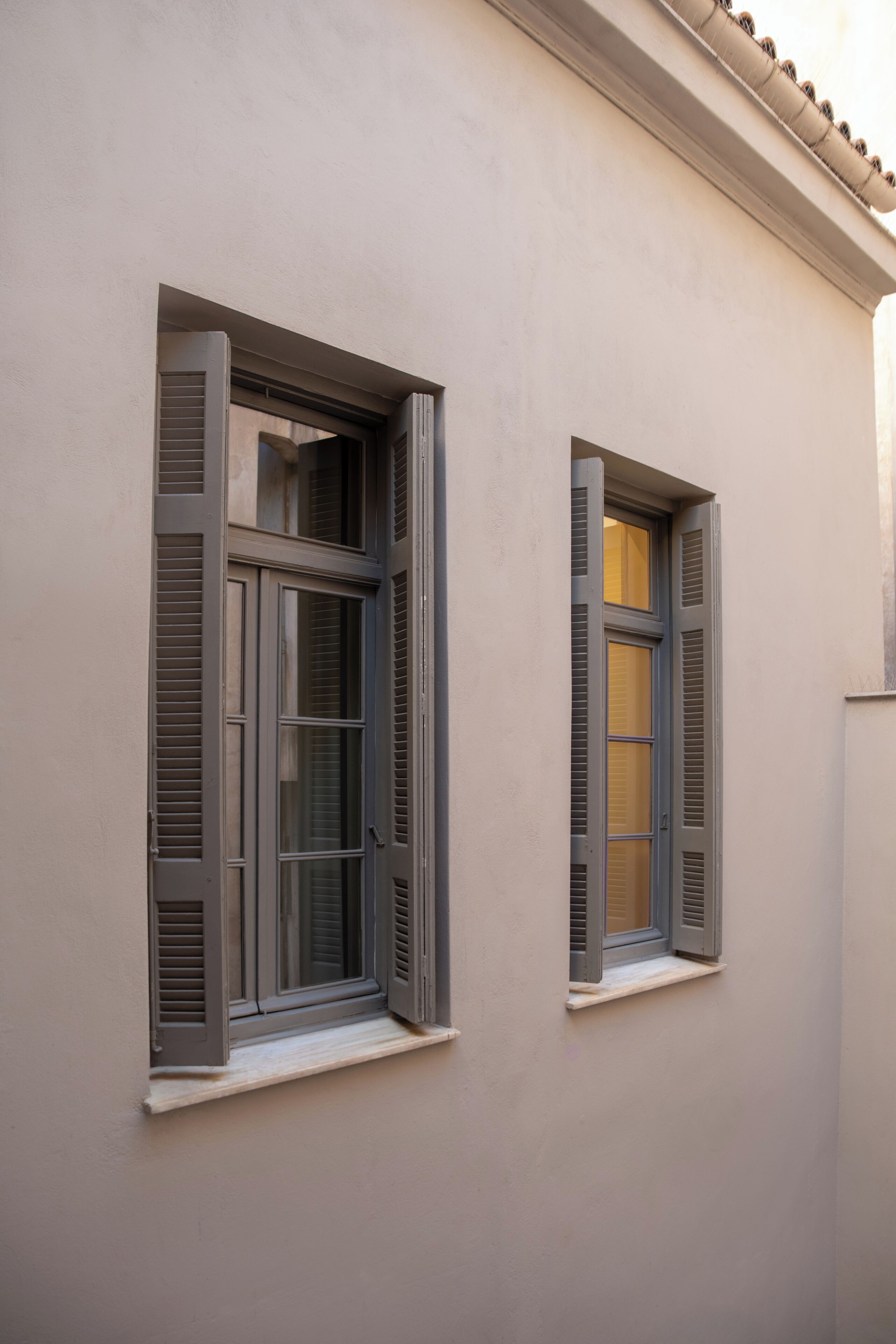 Un edificio con dos ventanas, cada una con contraventanas.