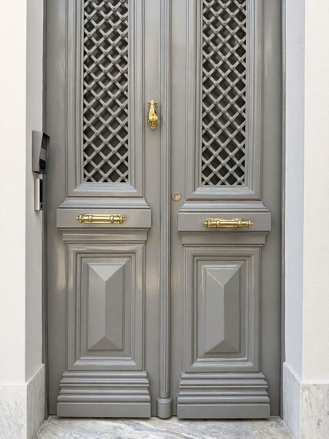 Uma porta dupla com fechadura e um olho de fechadura, acompanhada por duas maçanetas.
