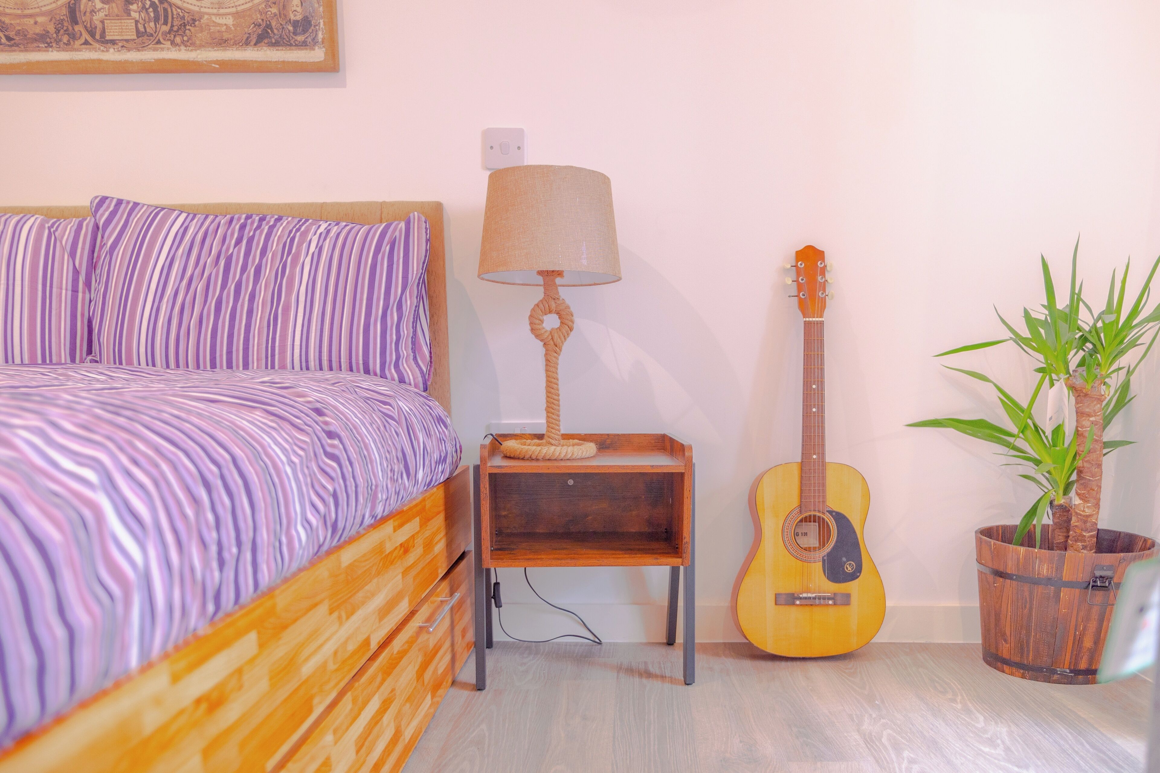 Un dormitorio con una cama, una lámpara, una guitarra y una planta en maceta.
