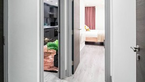 A hallway with a wooden floor leading to a bedroom with a bed and a window. - Bradford City Apartment - Bolton Road Oasis (Bradford)