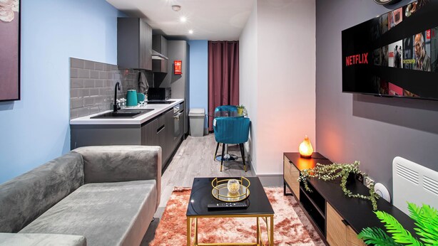 A modern living room with a sofa, coffee table, and a flat-screen TV displaying a Netflix interface. - Bradford City Apartment - Bolton Road Oasis (Bradford)