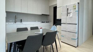 Une cuisine moderne avec des meubles blancs, un plan de travail gris et un réfrigérateur double encastré.