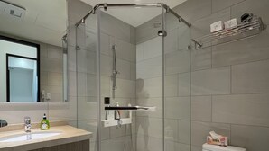 Une salle de bain moderne avec une douche à parois de verre, un lavabo doté d’un distributeur de savon et des toilettes.