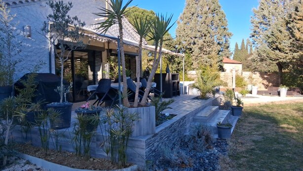 Una casa con patio que cuenta con mobiliario exterior y un camino de piedra.