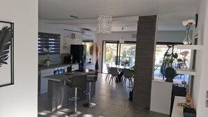 Una cocina moderna con una isla central, taburetes de bar y un comedor con vistas.